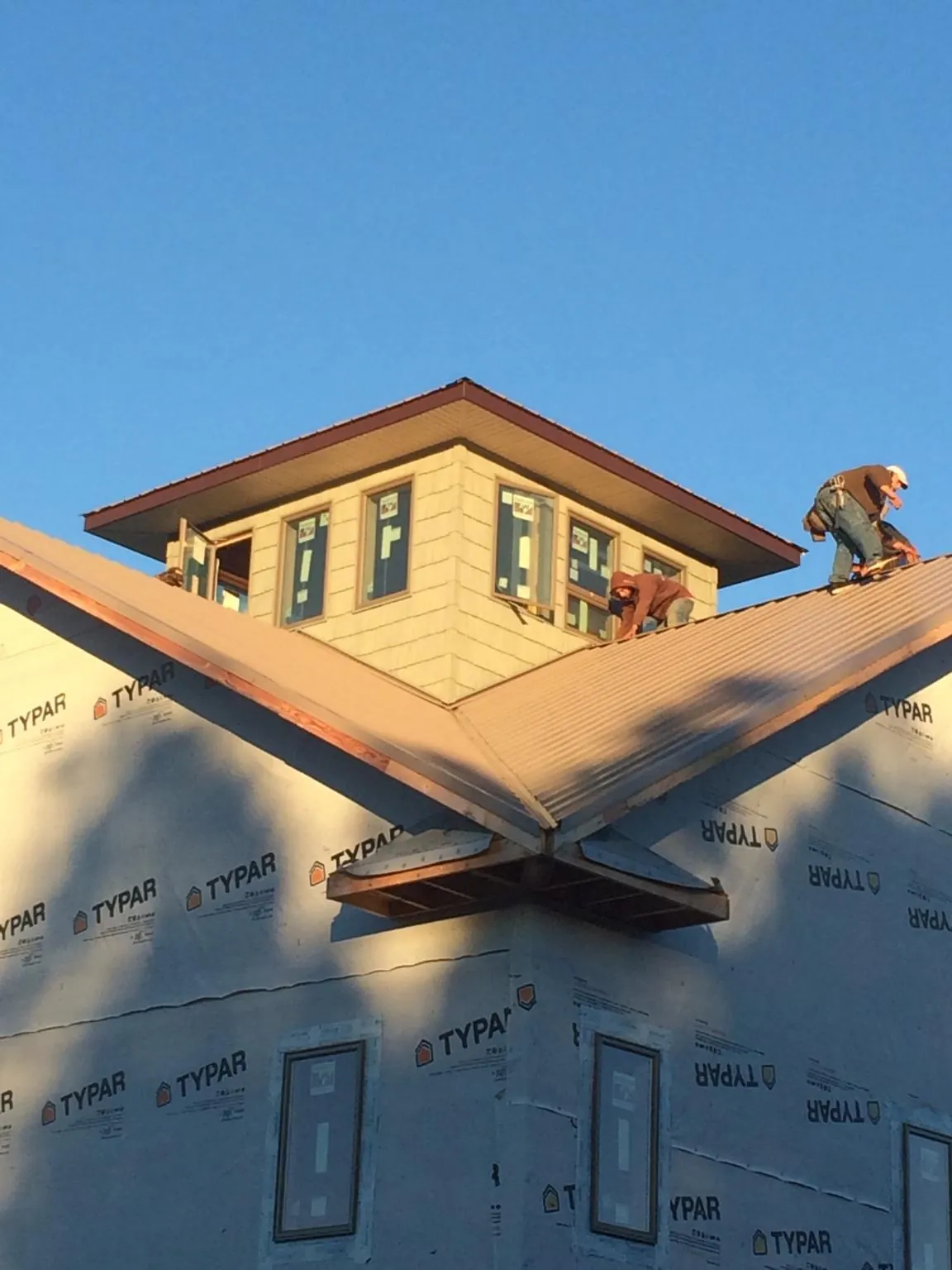 Roofers working around a rooftop cupola on a new metal roof at sunset — Roof Waterproofing in Avalon by Roofing Brothers